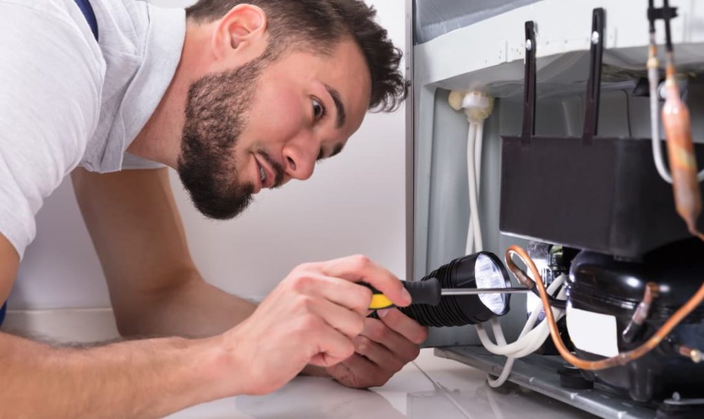 in-home appliance repair technician repairing dishwasher